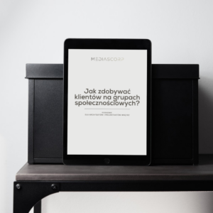 Tablet z e-bookiem o pozyskiwaniu klientów dla architektów i projektantów wnętrz leżący na półce między czarnymi pudełkami